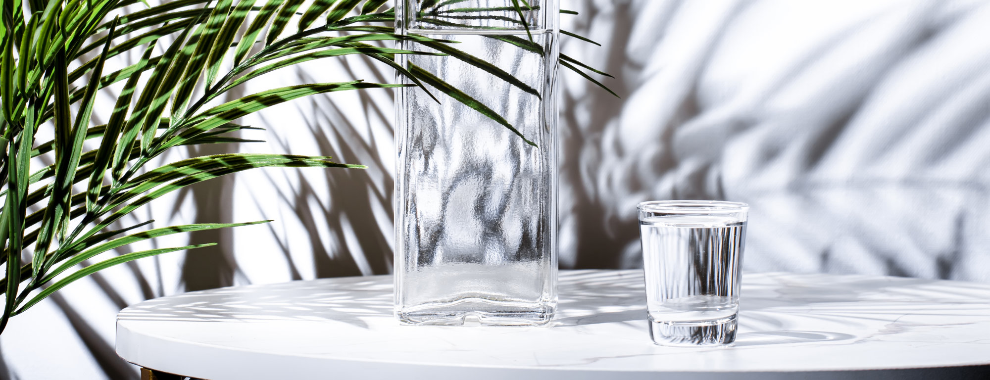 Vodka in glass and bottles of strong drink on white background, hard light